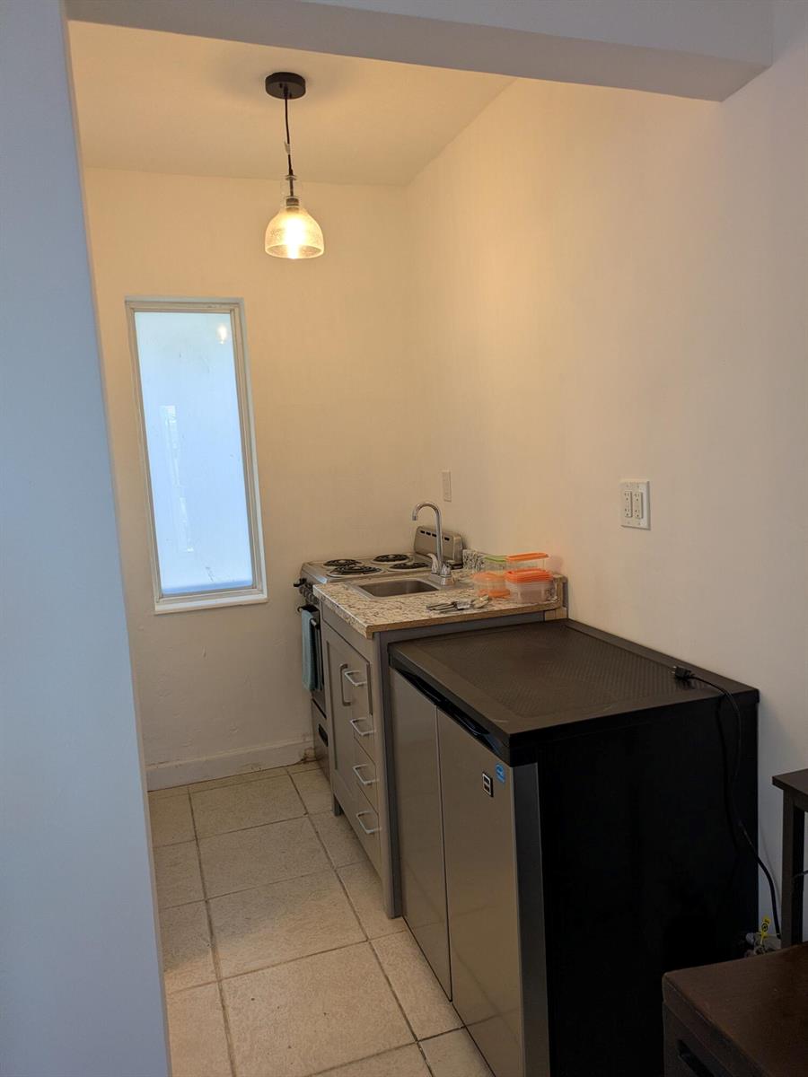 A small kitchen features a compact stove, sink, countertop, and a black mini-fridge — 3312 SE 4th Street # 3, Pompano Beach FL 33062, POMPANO BEACH, FL