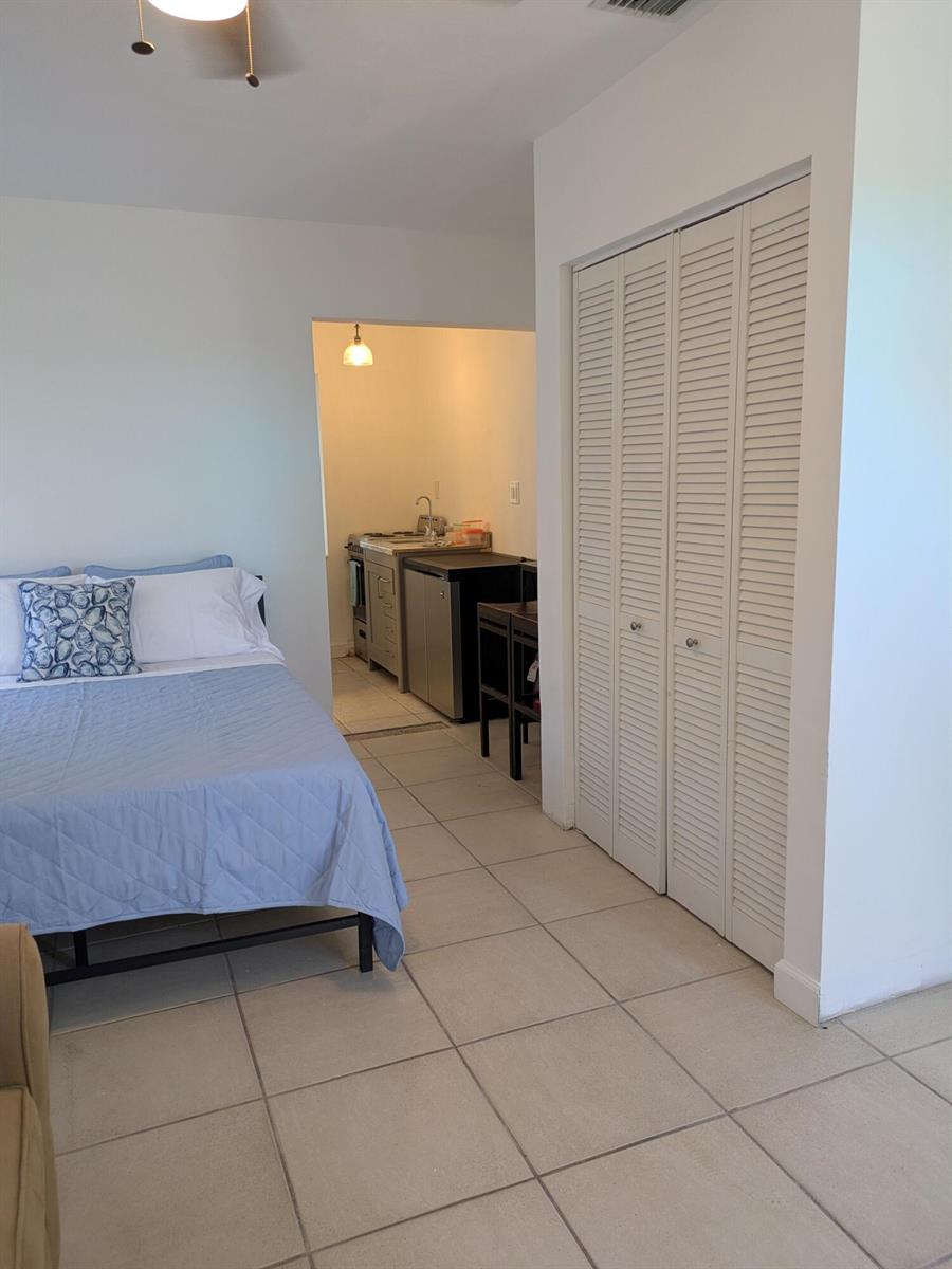 A bedroom with a blue bedspread and a small kitchenette area with tiled flooring — 3312 SE 4th Street # 3, Pompano Beach FL 33062, POMPANO BEACH, FL