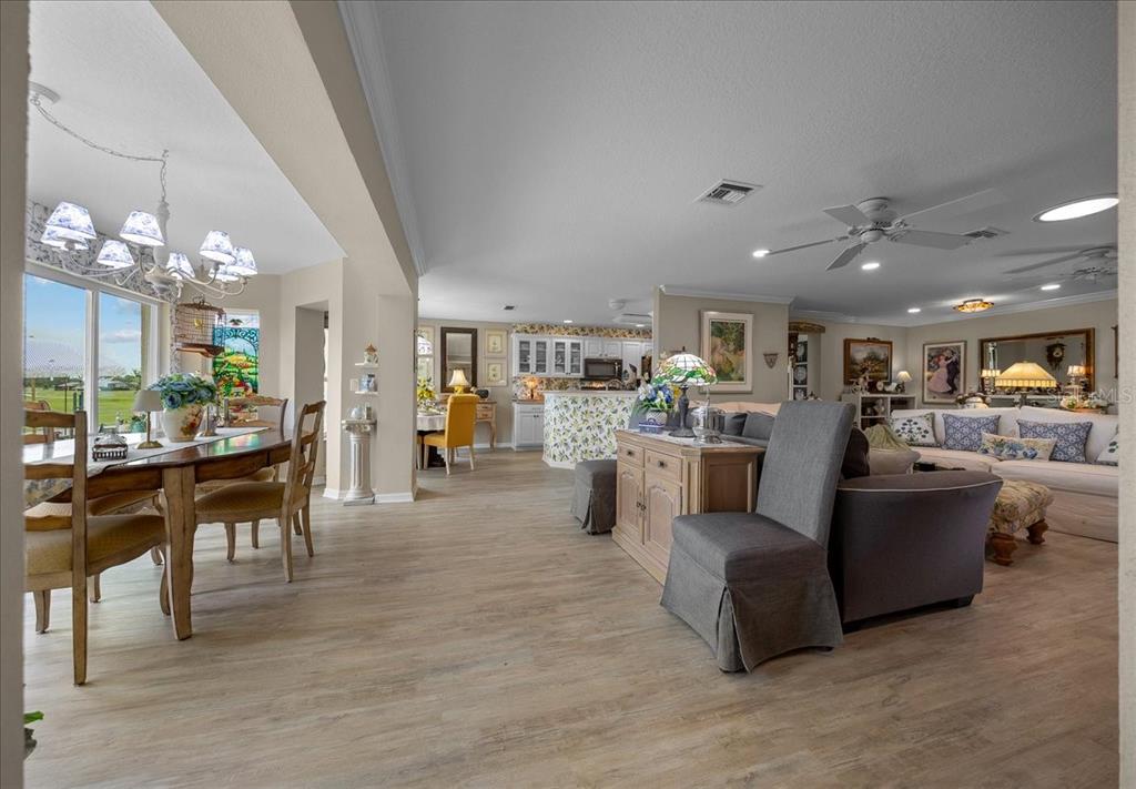An open-concept living and dining area with light wood-look flooring and a kitchen in back — 8998 SW 99TH COURT ROAD, OCALA, FL