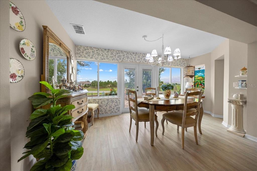 A dining room features a wooden table, chairs, a hutch, and large windows overlooking outdoors — 8998 SW 99TH COURT ROAD, OCALA, FL