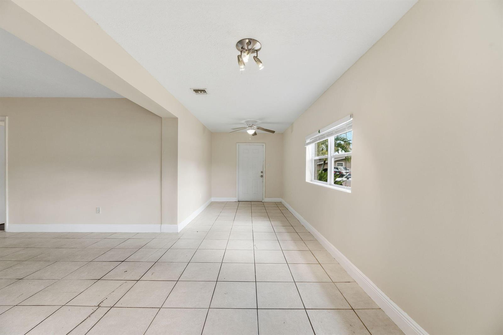 An empty room features beige walls, light-colored floor tiles, a ceiling fan, and a window — 5131 SW 6th Street, Margate FL 33068, MARGATE, FL