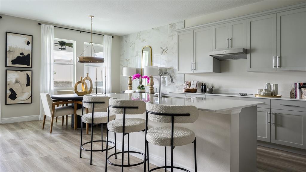 A modern kitchen features light gray cabinets, a marble backsplash, and a large island — 33619 TWILIGHT SEA PLACE, DADE CITY, FL