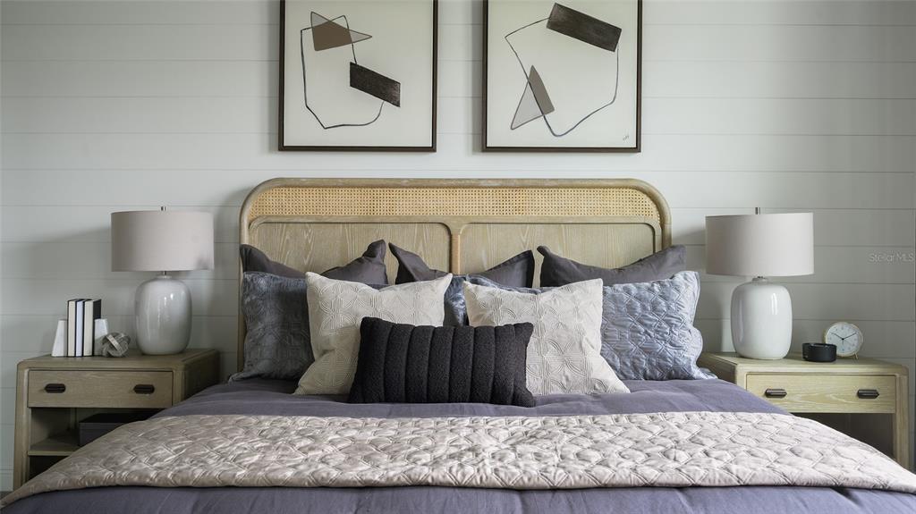 A bedroom features a cane headboard, shiplap walls, two nightstands, and abstract framed artwork — 33619 TWILIGHT SEA PLACE, DADE CITY, FL