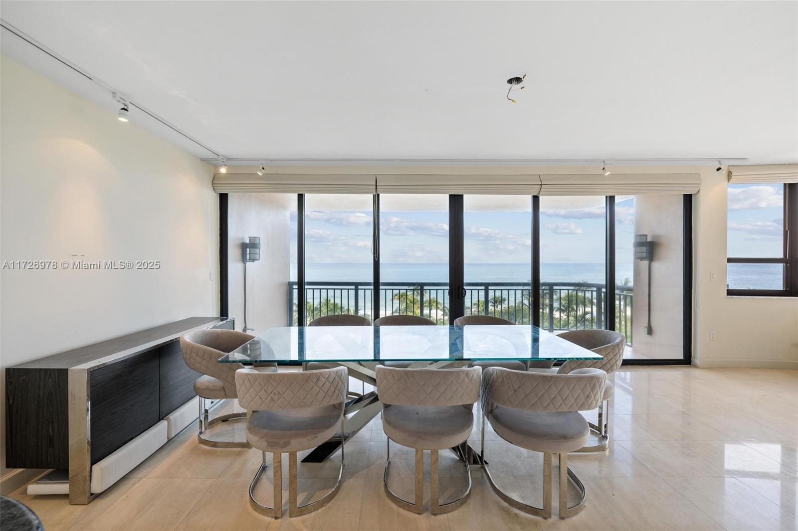 A dining room with a glass table, eight upholstered chairs, and floor-to-ceiling windows overlooking the ocean — 10175 Collins Ave # 502, Bal Harbour FL 33154, BAL HARBOUR, FL