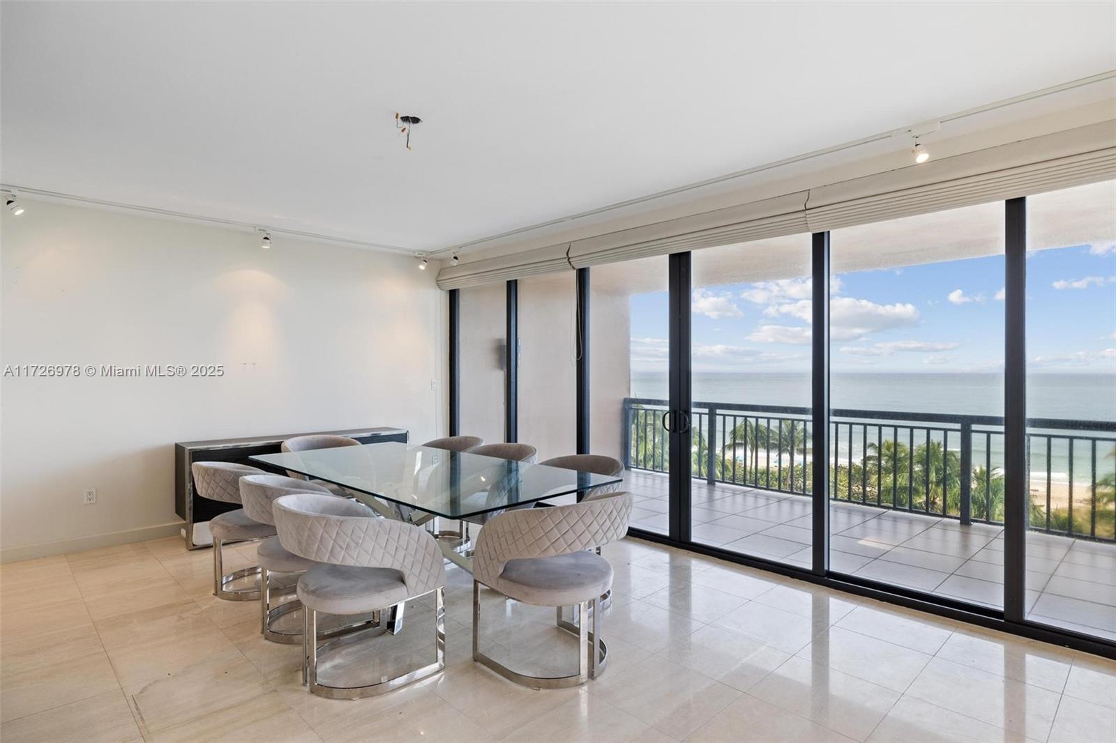 A dining room with a glass table, upholstered chairs, and a balcony overlooking the ocean — 10175 Collins Ave # 502, Bal Harbour FL 33154, BAL HARBOUR, FL