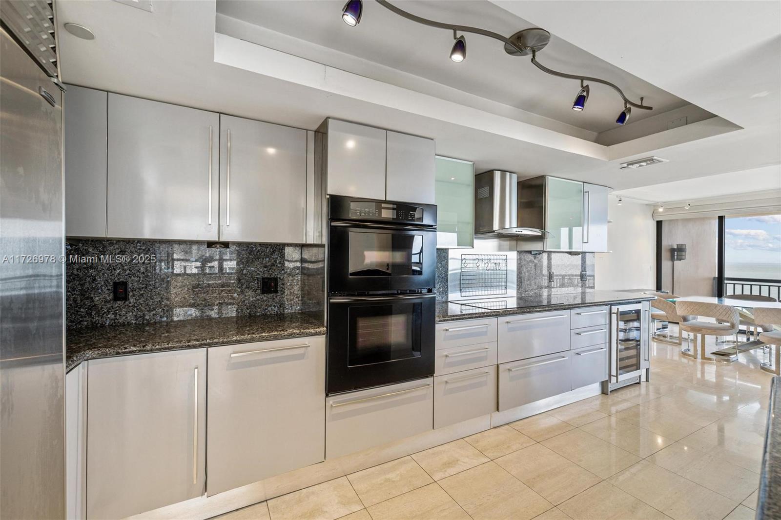 A modern kitchen features gray cabinets, granite countertops, stainless steel appliances, and tile flooring — 10175 Collins Ave # 502, Bal Harbour FL 33154, BAL HARBOUR, FL