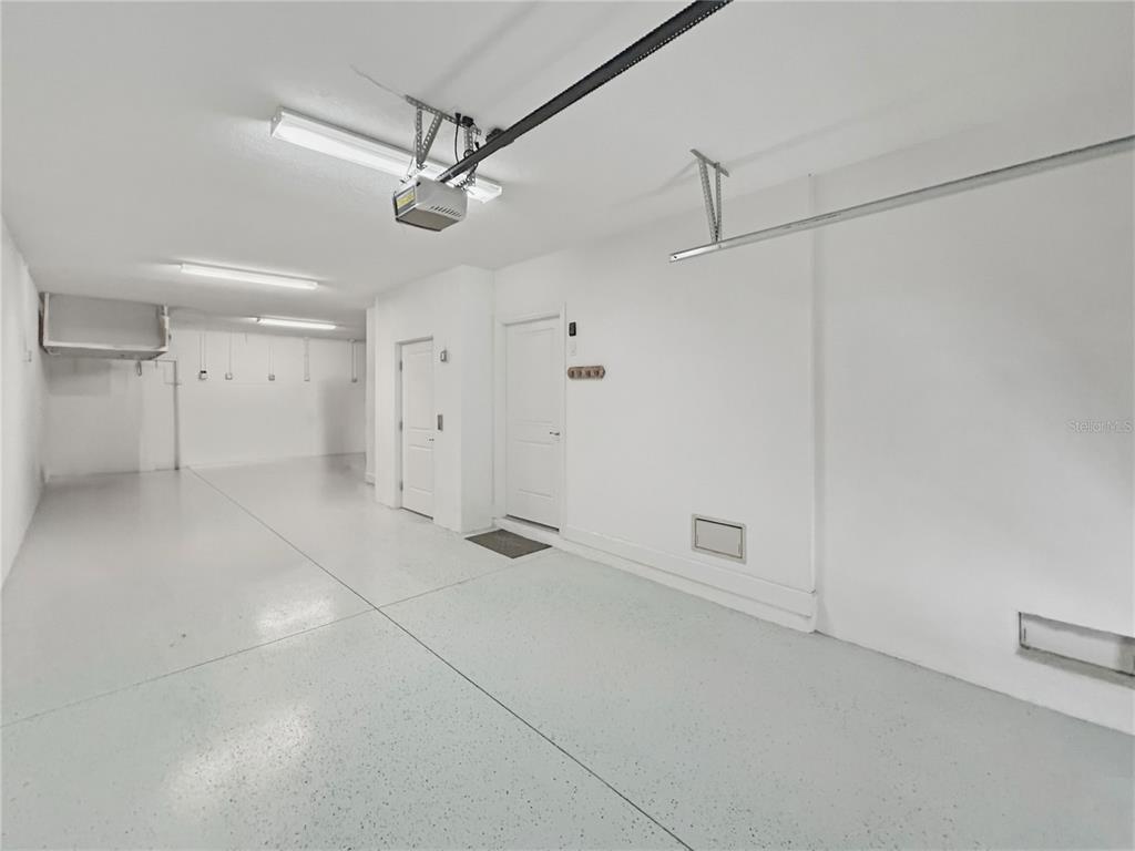 A clean, white-walled garage features a speckled epoxy floor and two interior doors — 3137 MOORINGS DRIVE S, ST PETERSBURG, FL