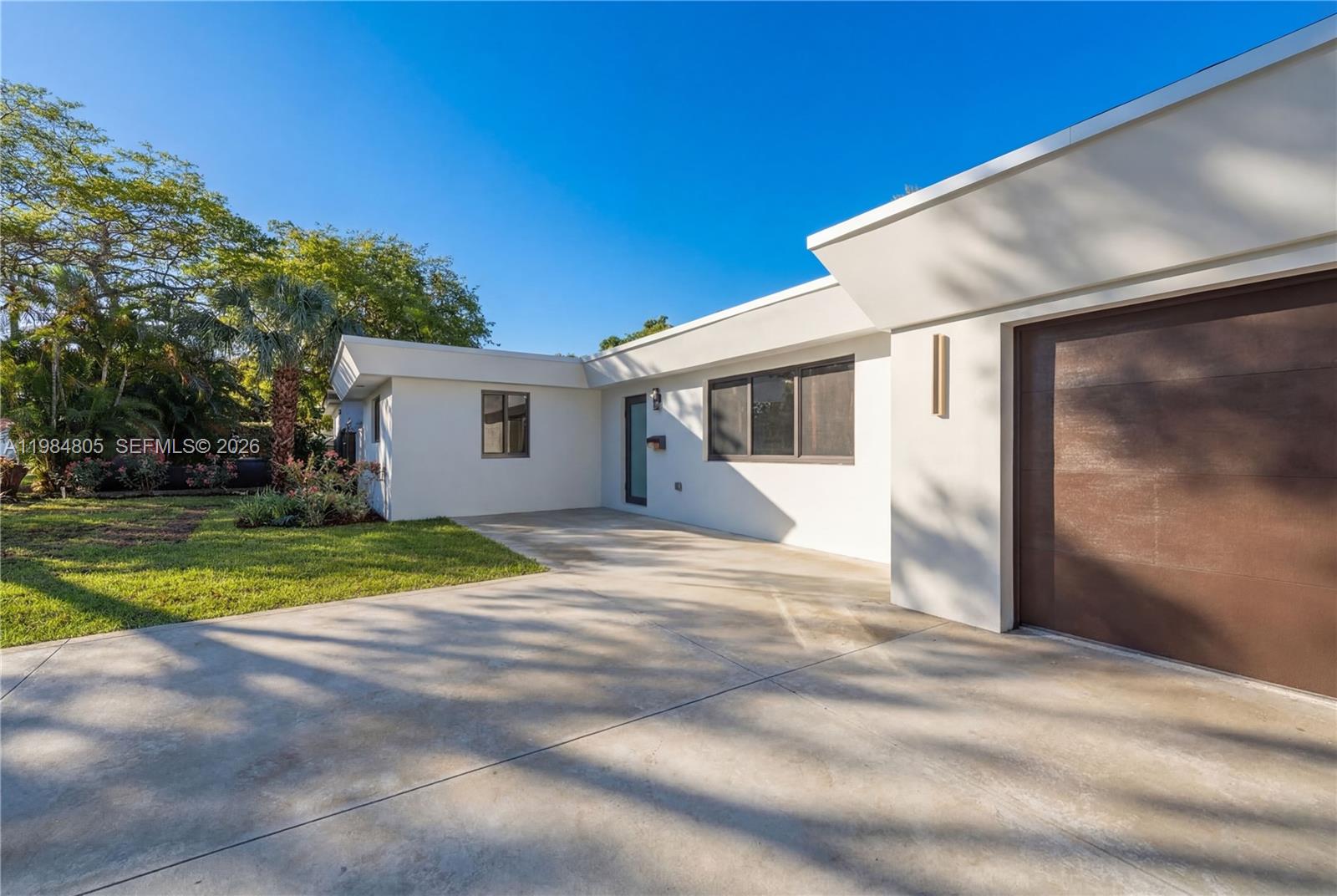 A white exterior house with a brown garage door and a concrete driveway — 10910 NE 9th Ct, Biscayne Park FL 33161, BISCAYNE PARK, FL