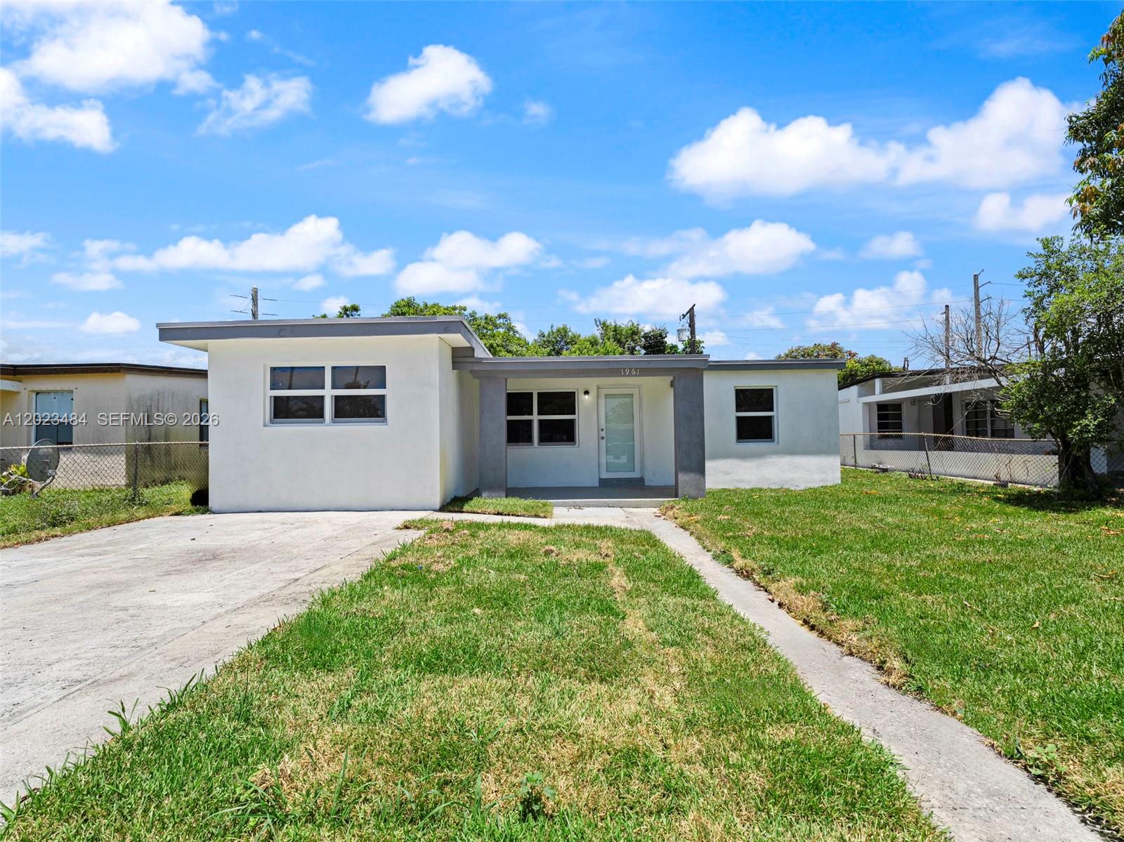A single-story white house with a flat roof and a concrete driveway under a blue sky — 1961 Rutland St, Opa-Locka FL 33054, OPA-LOCKA, FL