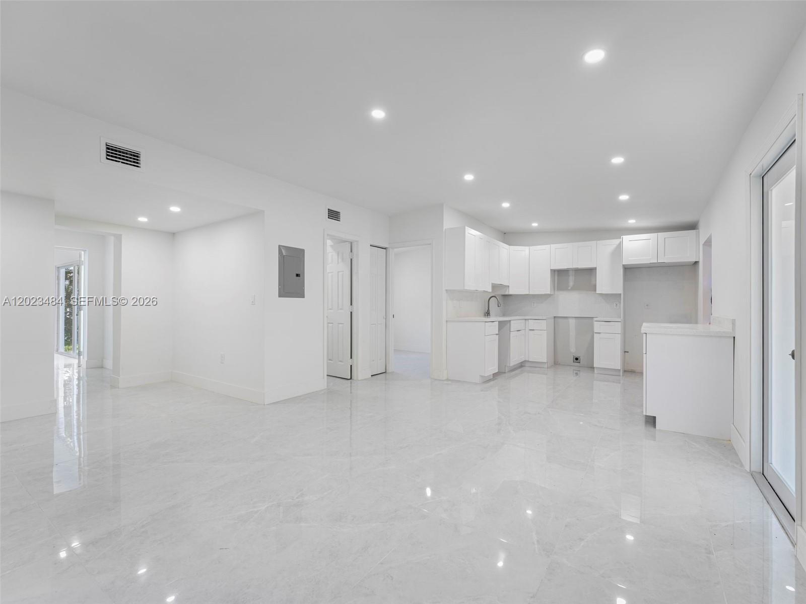A bright, open-concept kitchen and living area features white cabinetry and polished tile flooring — 1961 Rutland St, Opa-Locka FL 33054, OPA-LOCKA, FL