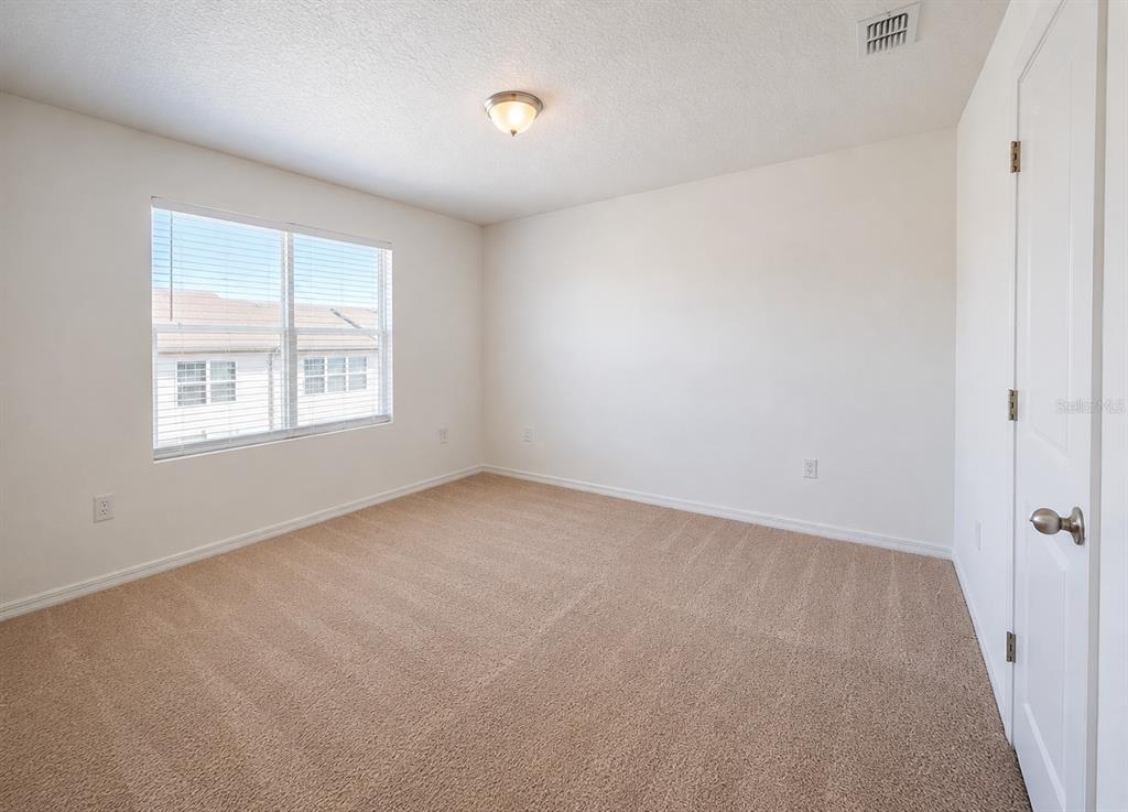 An empty bedroom features beige carpet, white walls, a single window, and a closet door — 936 GRANDIN STREET, DAVENPORT, FL