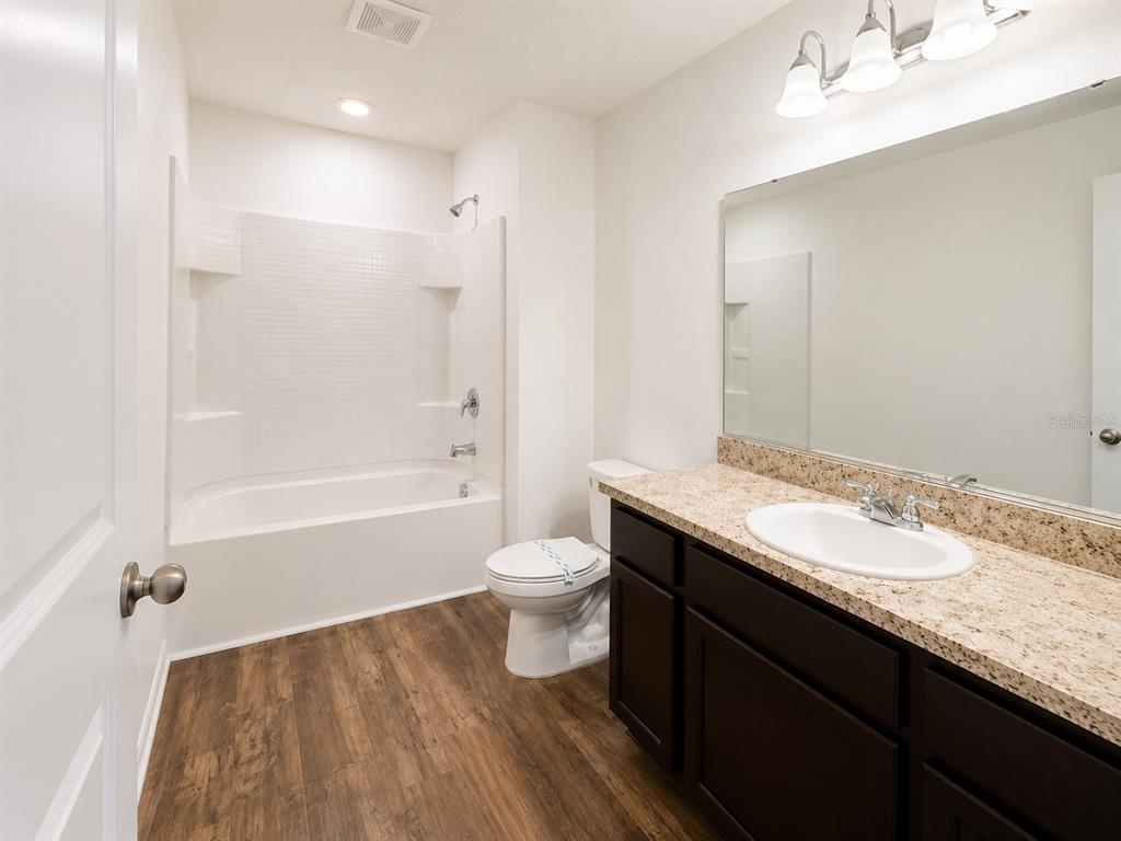 A bathroom features a tub-shower combo, a dark wood vanity, and wood-look flooring — 936 GRANDIN STREET, DAVENPORT, FL