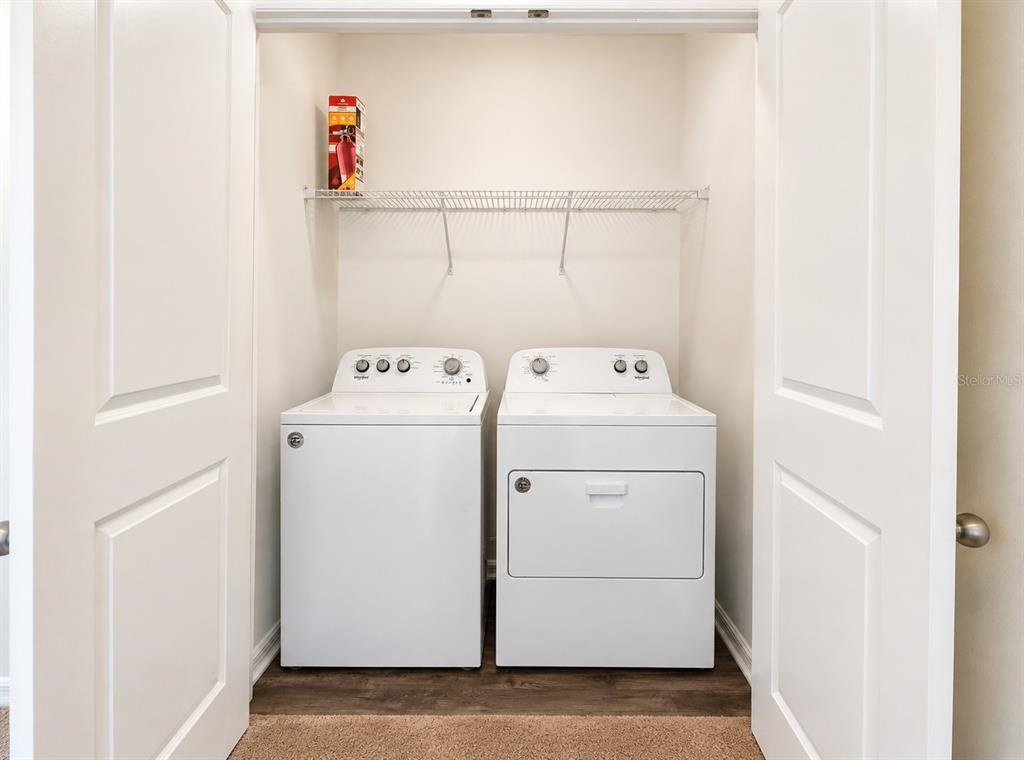A laundry closet features a white top-load washer and dryer beneath a wire shelf — 936 GRANDIN STREET, DAVENPORT, FL