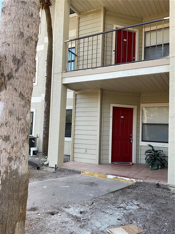 A two-story apartment building exterior features tan siding, red doors, and a concrete patio — 3028 PARKWAY BOULEVARD UNIT 105, KISSIMMEE, FL