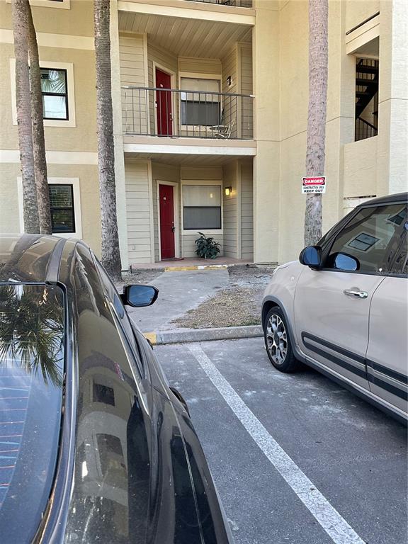 A two-story apartment building exterior features red doors, balconies, and a parking lot — 3028 PARKWAY BOULEVARD UNIT 105, KISSIMMEE, FL