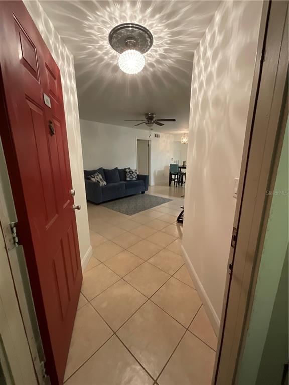An entryway with a red door leads into a living room with tiled floors — 3028 PARKWAY BOULEVARD UNIT 105, KISSIMMEE, FL