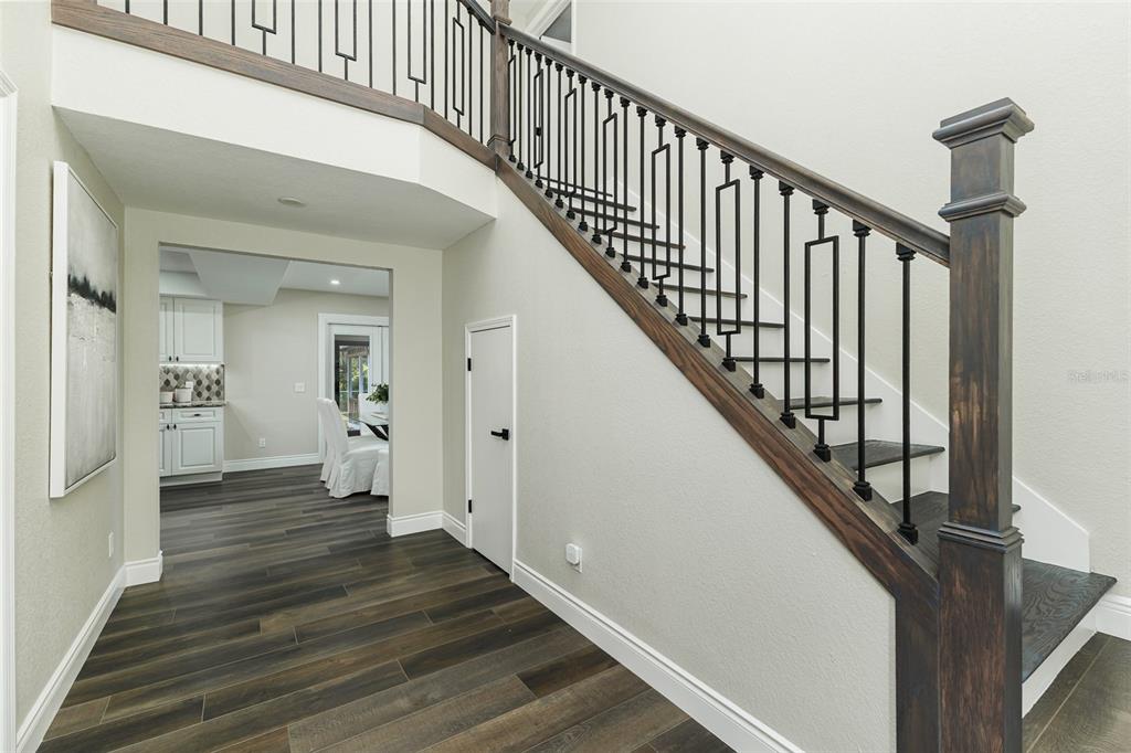 A staircase with dark wood treads and black metal railings leads up from a foyer — 3415 IMPERIAL LANE, LAKELAND, FL