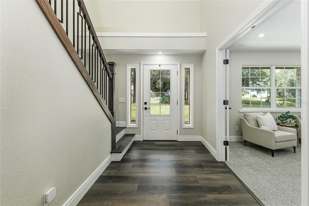 An entryway features dark wood flooring, a staircase with black railings, and a white front door — 3415 IMPERIAL LANE, LAKELAND, FL