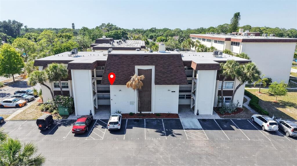 An aerial view shows a multi-story apartment building with a parking lot in front — 6370 1ST STREET N UNIT 202, ST PETERSBURG, FL