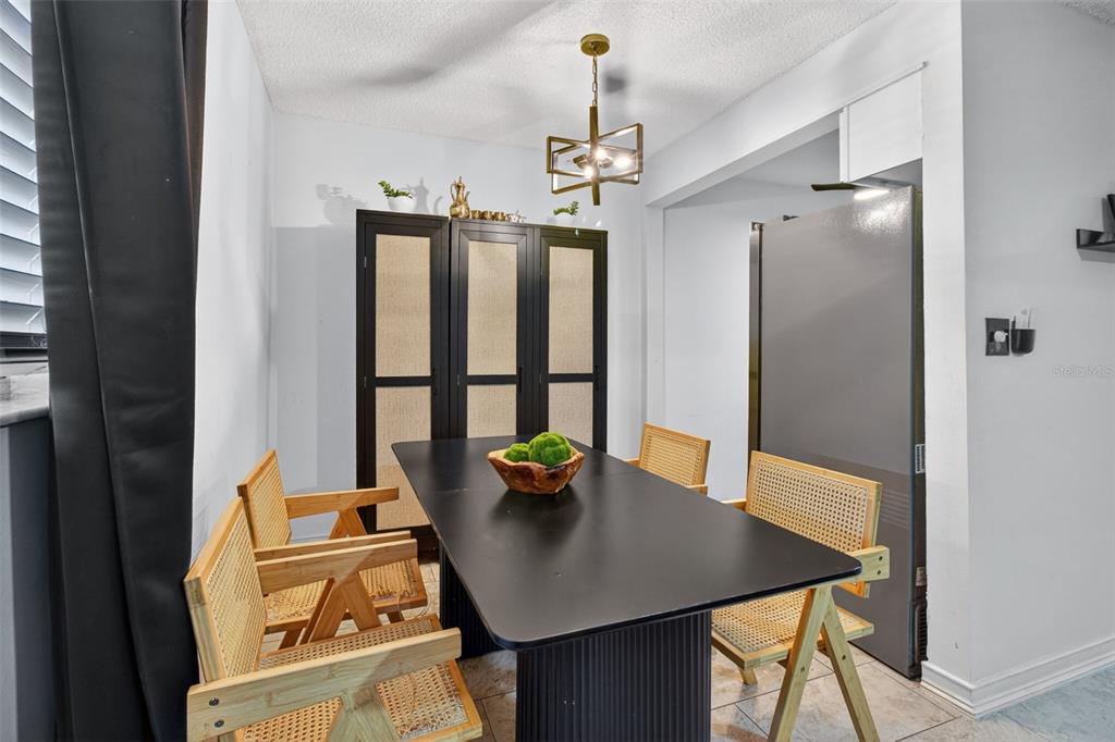 A dining room features a black table, four cane chairs, and a modern geometric chandelier — 6370 1ST STREET N UNIT 202, ST PETERSBURG, FL