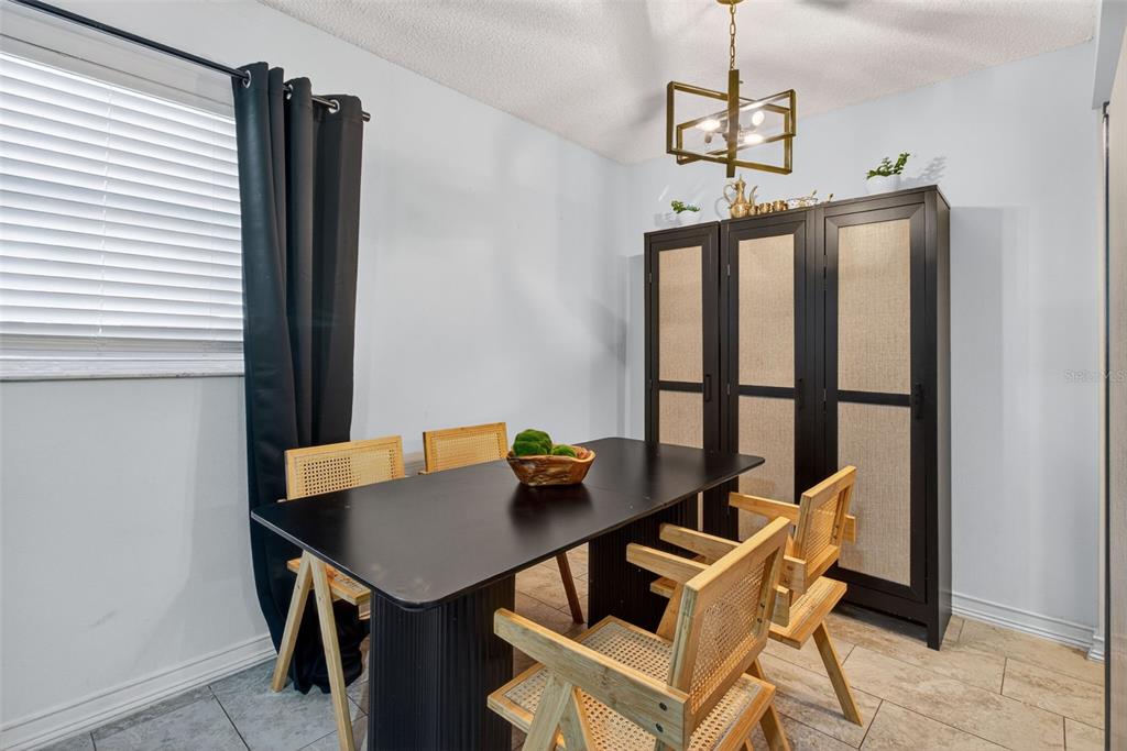 A dining room features a black table, cane-back chairs, and a tall black storage cabinet — 6370 1ST STREET N UNIT 202, ST PETERSBURG, FL
