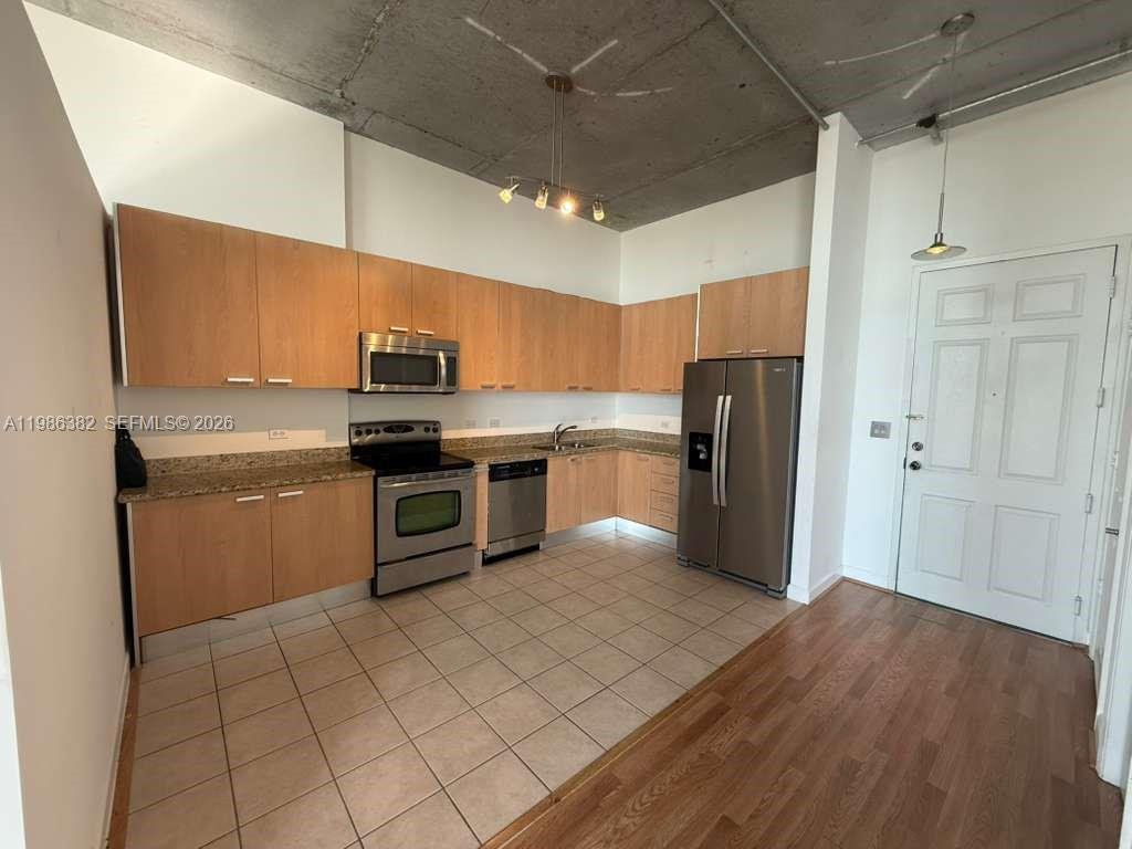 A kitchen with light wood cabinets, stainless steel appliances, and an exposed concrete ceiling — 2100 Van Buren St # 501, Hollywood FL 33020, HOLLYWOOD, FL