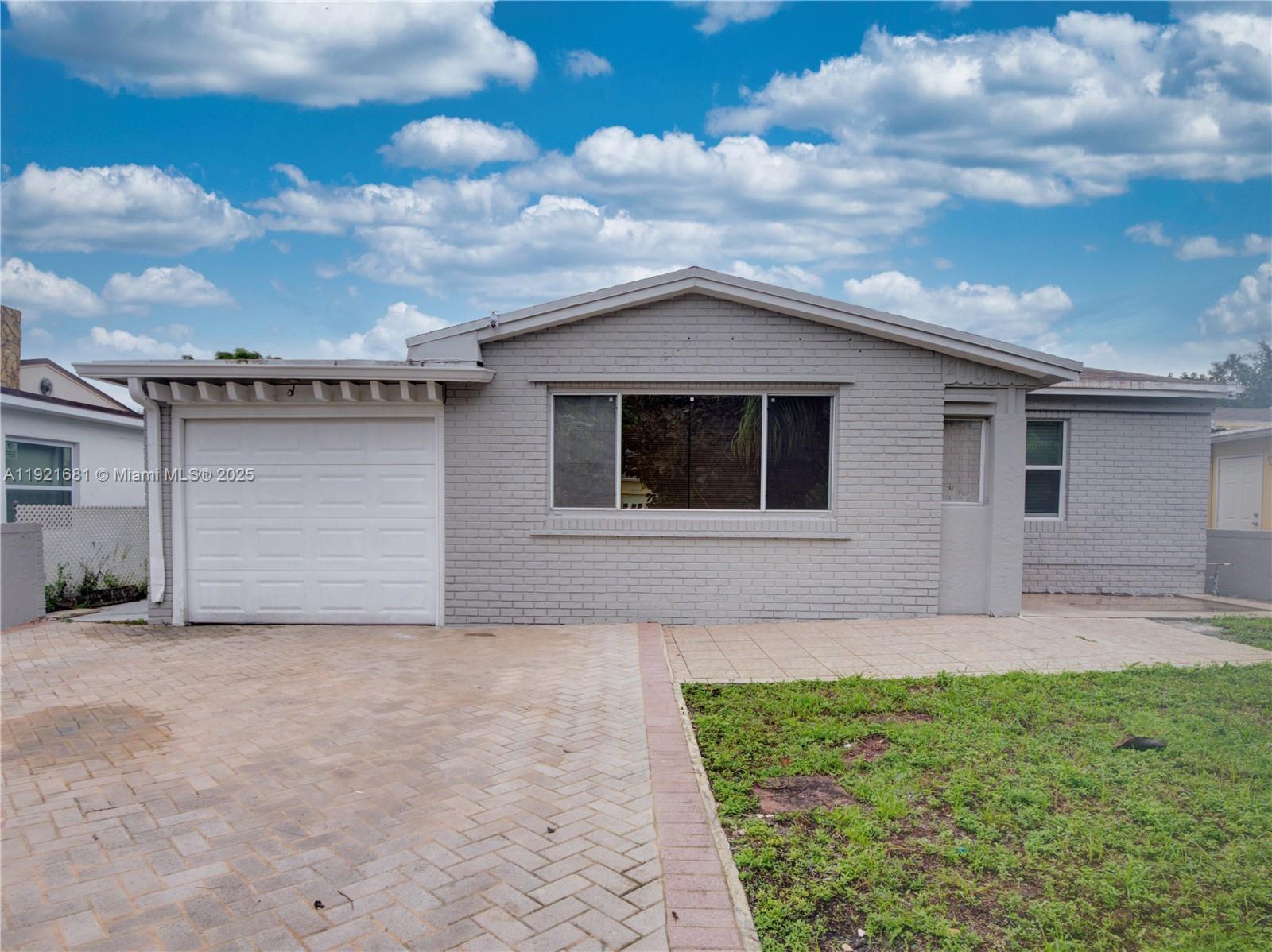 A single-story gray brick house features a white garage door and a paved driveway — 2703 Adams St, Hollywood FL 33020, HOLLYWOOD, FL