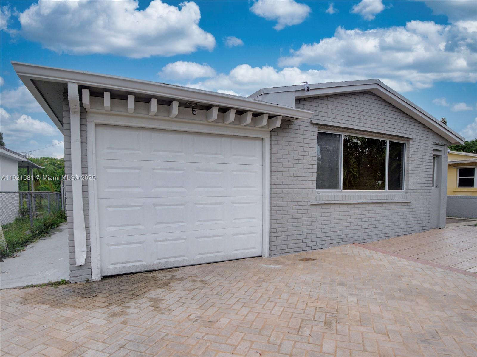 A gray brick house features a white garage door and a paved driveway — 2703 Adams St, Hollywood FL 33020, HOLLYWOOD, FL