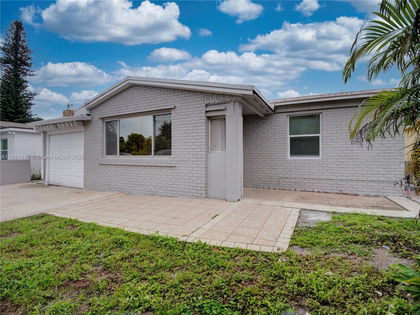 A single-story gray brick house features a white garage door and a paved front patio — 2703 Adams St, Hollywood FL 33020, HOLLYWOOD, FL