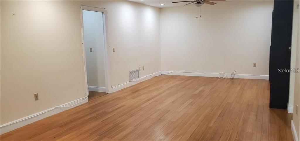 An empty room features light wood flooring, beige walls, a ceiling fan, and a doorway — 637 PEACHWOOD DRIVE, ALTAMONTE SPRINGS, FL