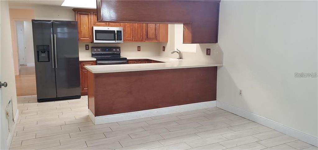 A kitchen features wood cabinets, a breakfast bar, stainless steel appliances, and light tile flooring — 637 PEACHWOOD DRIVE, ALTAMONTE SPRINGS, FL
