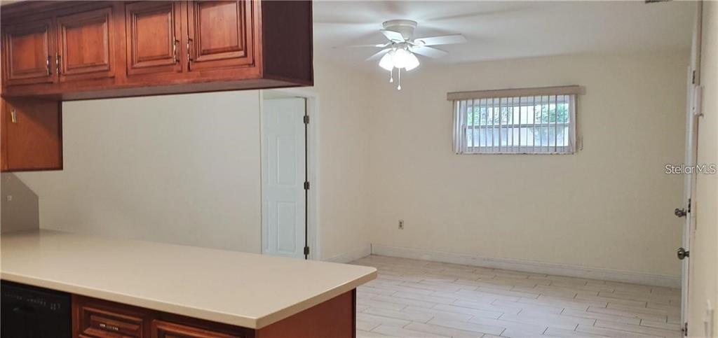 A kitchen with wood cabinets and a counter overlooks an adjacent room with tile flooring — 637 PEACHWOOD DRIVE, ALTAMONTE SPRINGS, FL