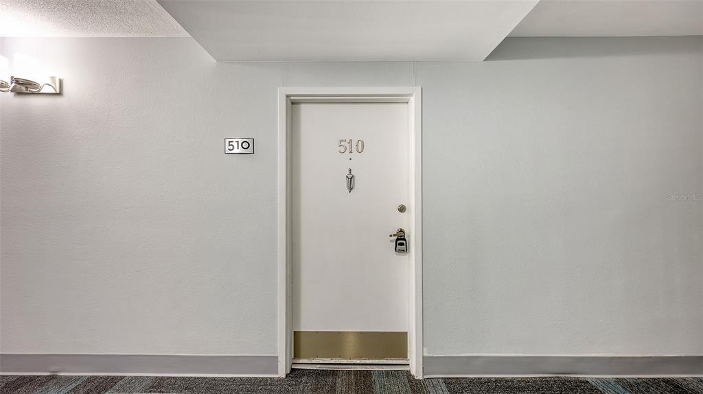 A white apartment door labeled 510 is centered on a plain gray hallway wall — 5855 MIDNIGHT PASS ROAD UNIT 510, SARASOTA, FL