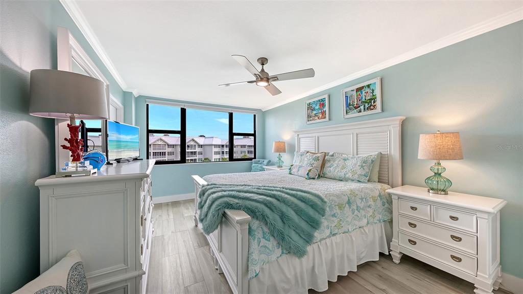 A bedroom features a king bed, white furniture, light blue walls, and a ceiling fan — 5855 MIDNIGHT PASS ROAD UNIT 510, SARASOTA, FL