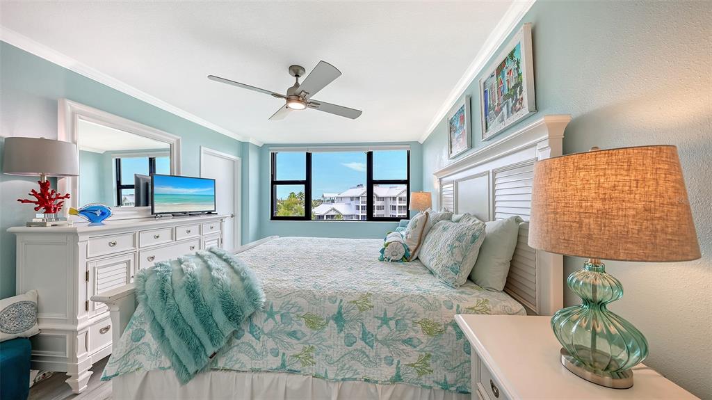 A bedroom features a king bed, white furniture, light blue walls, and a ceiling fan — 5855 MIDNIGHT PASS ROAD UNIT 510, SARASOTA, FL