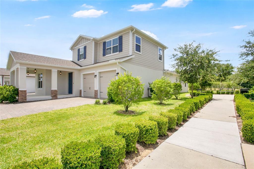 A two-story house with a two-car garage, beige siding, and a landscaped front yard — 9481 EMERALD BERRY DRIVE, WINTER GARDEN, FL