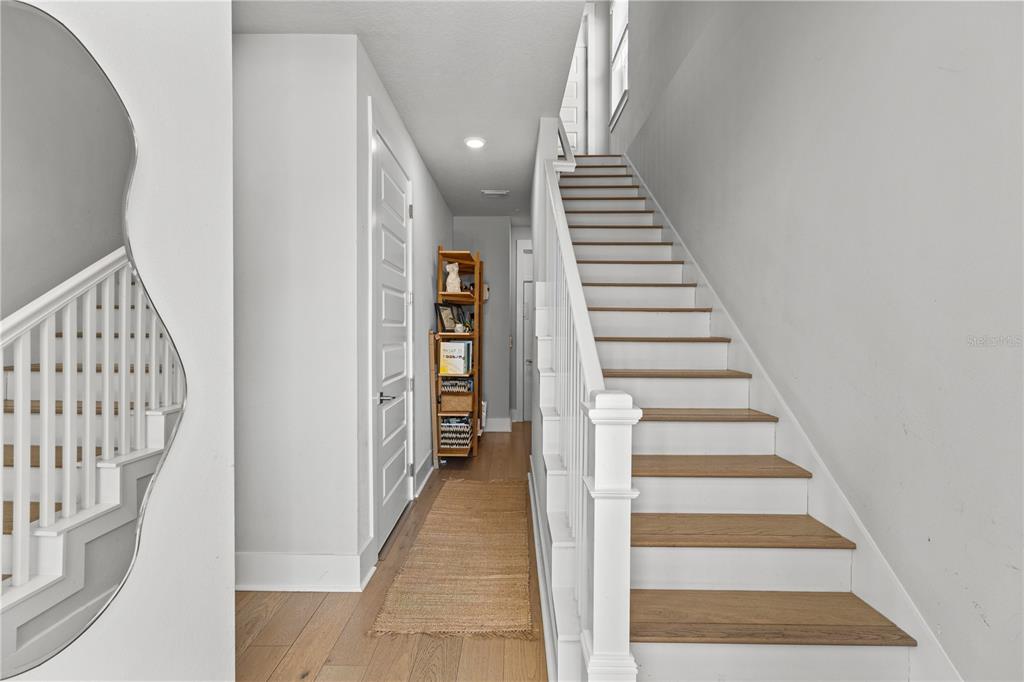 A staircase with wooden treads and white risers leads upward beside a hallway with flooring — 501 LAFAYETTE COURT, SARASOTA, FL