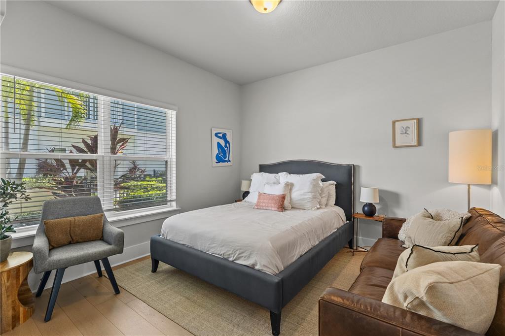 A bedroom features a dark upholstered bed, a leather sofa, and a gray accent chair — 501 LAFAYETTE COURT, SARASOTA, FL