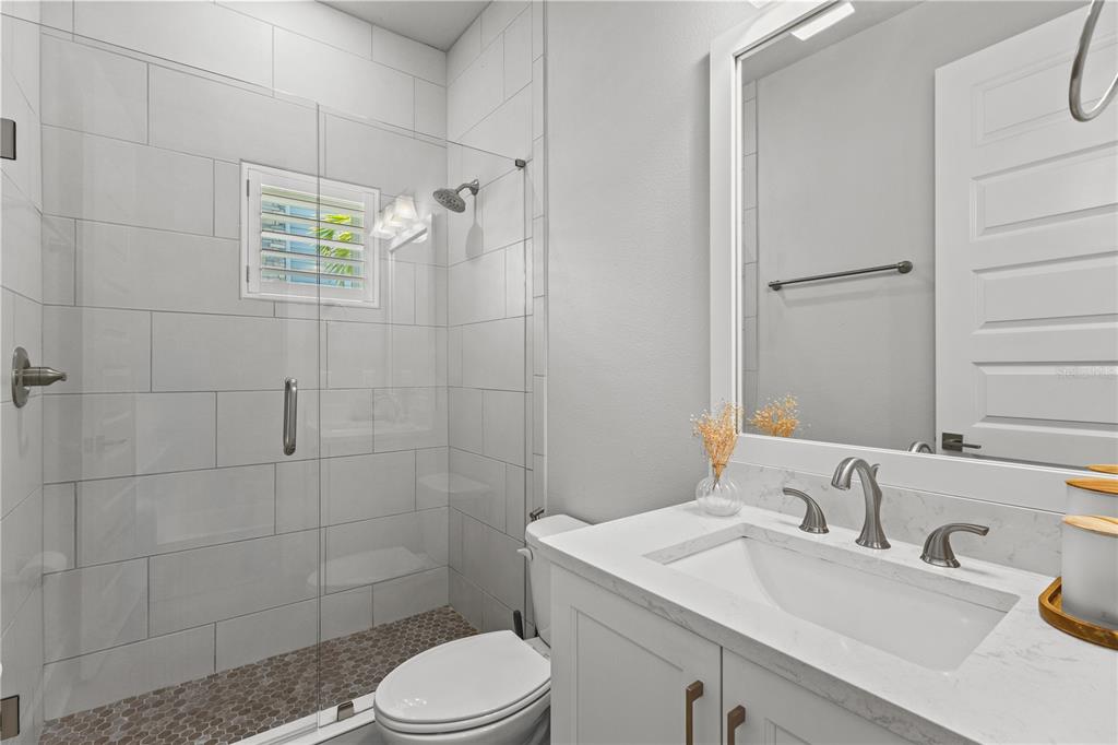 A bathroom features a glass-enclosed shower with tiled walls, a white vanity, and a toilet — 501 LAFAYETTE COURT, SARASOTA, FL