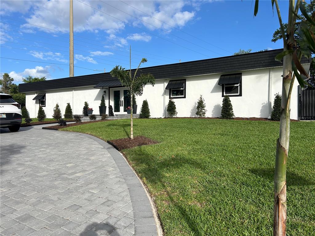 A white, single-story house with a black roof and black window awnings — 5701 TARAWOOD DRIVE, ORLANDO, FL