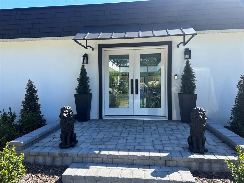 A white house exterior features a double glass door entrance with a metal awning — 5701 TARAWOOD DRIVE, ORLANDO, FL