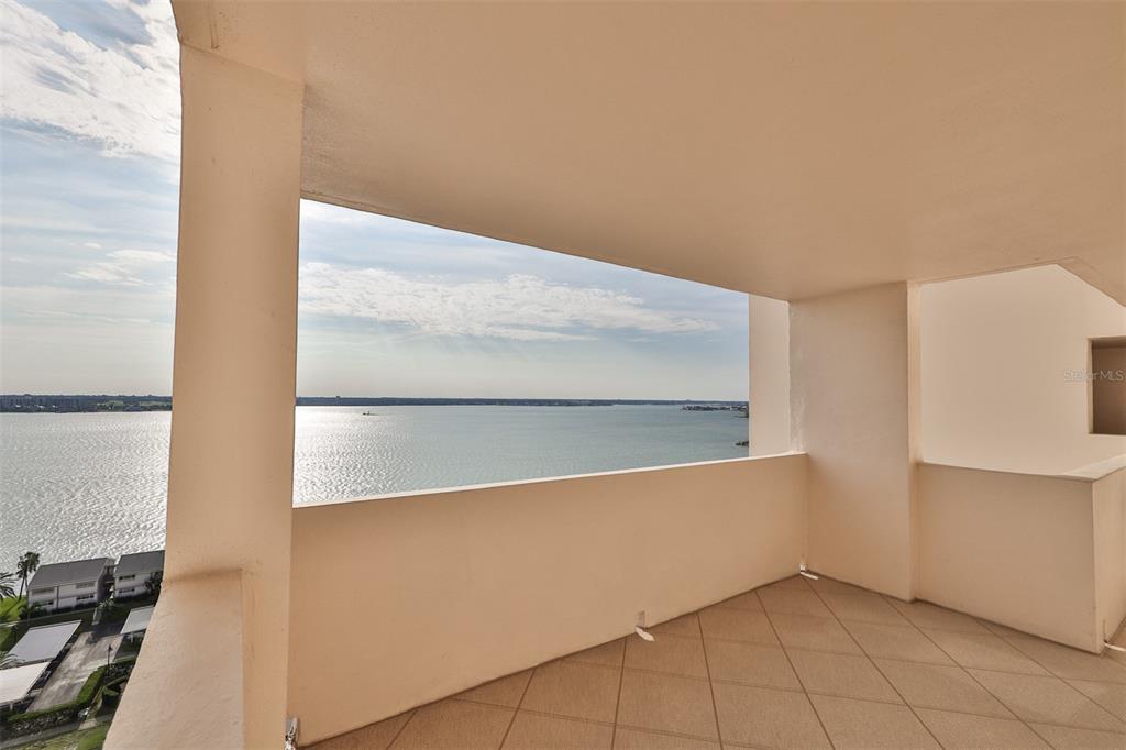 A covered balcony features tiled flooring and an expansive view of a large body of water — 1270 GULF BOULEVARD UNIT 1706, CLEARWATER BEACH, FL