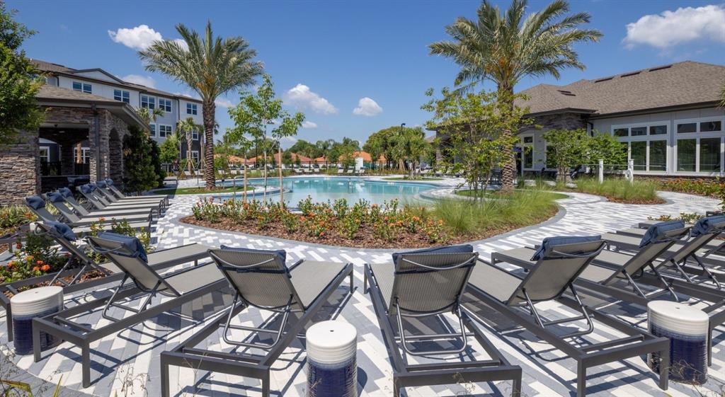 A swimming pool area with lounge chairs on a paved deck surrounded by palm trees — 3110 GOWAN DRIVE UNIT A1, WINTER HAVEN, FL