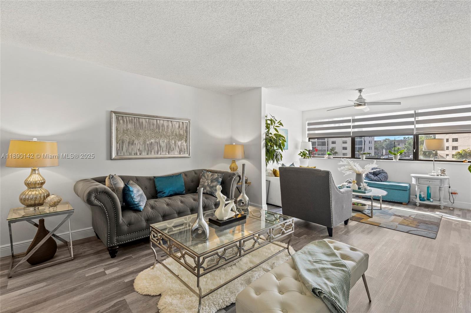 A living room features a gray tufted sofa, glass coffee table, and light wood flooring — 10400 NW 30th Ct # 202, Sunrise FL 33322, SUNRISE, FL