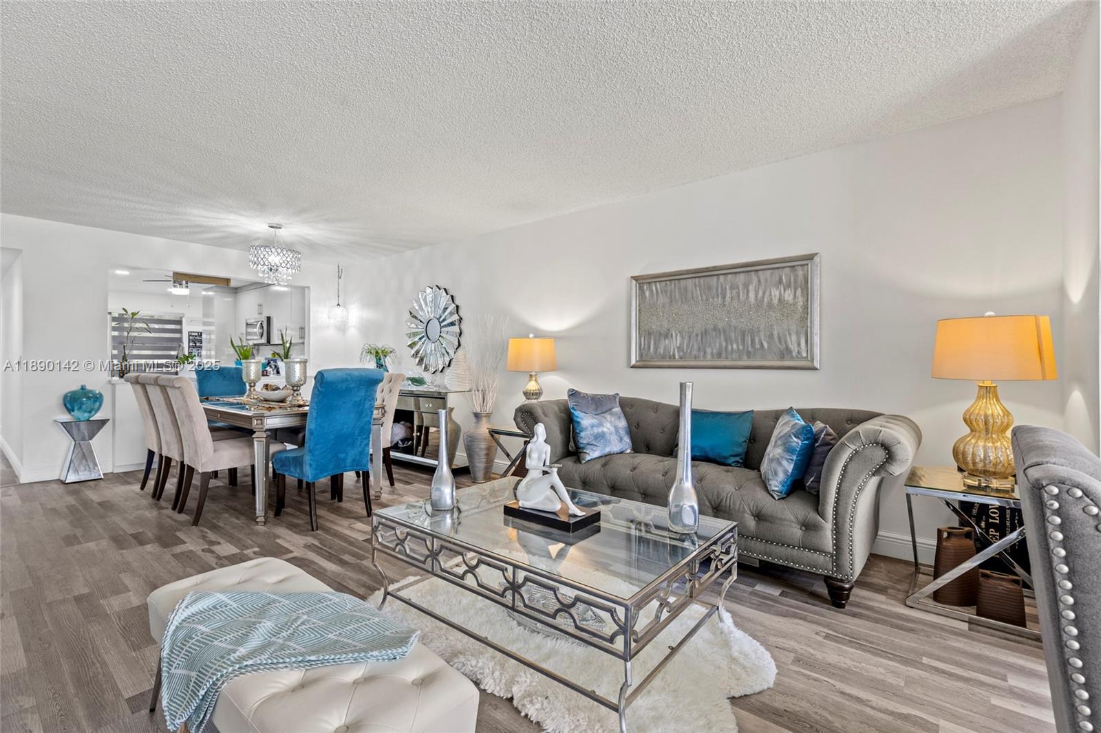 A living and dining room features grey wood-look flooring, a tufted sofa, and glass tables — 10400 NW 30th Ct # 202, Sunrise FL 33322, SUNRISE, FL