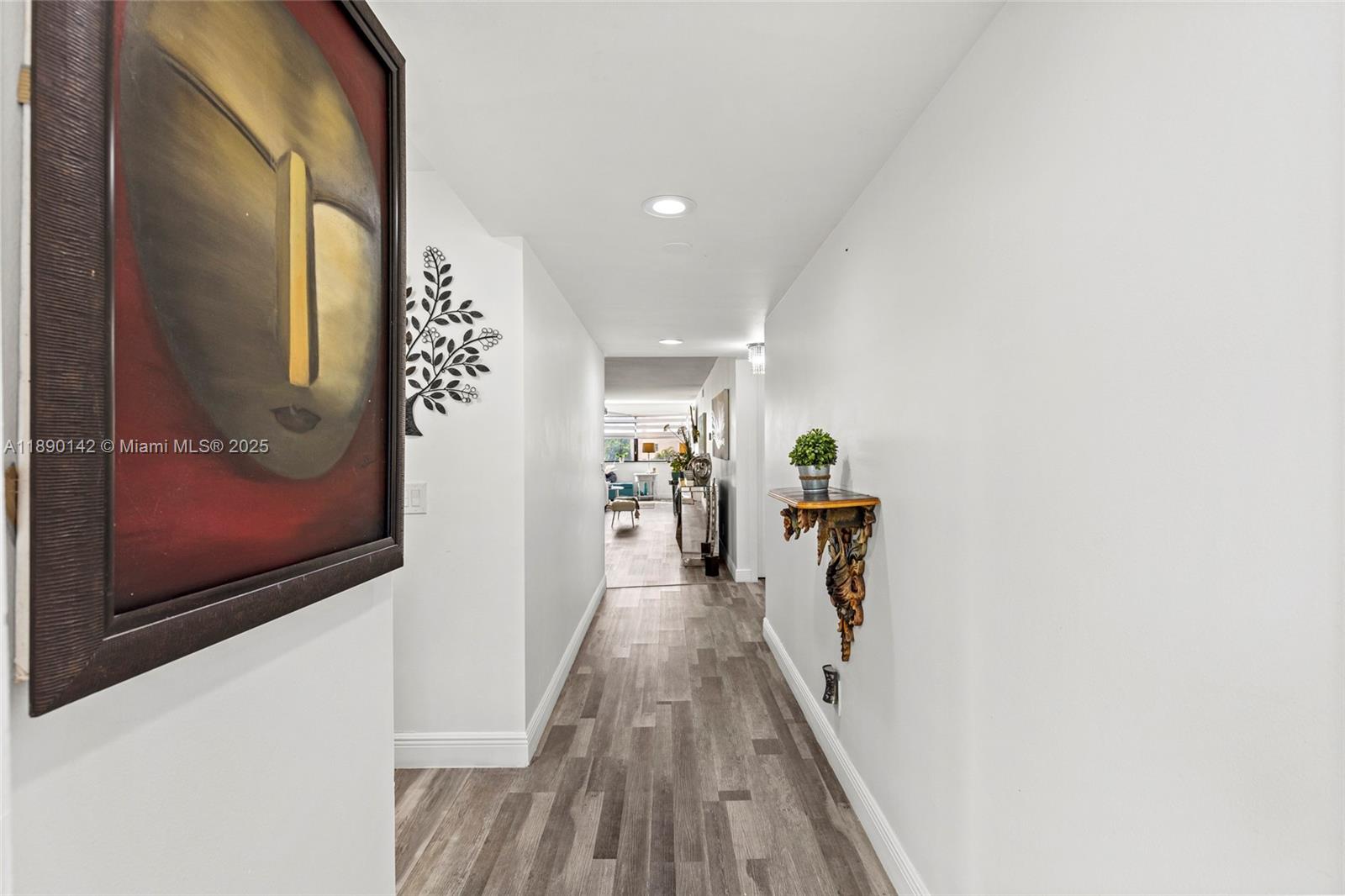 A hallway with wood-look flooring features a wall-mounted decorative shelf and a large framed painting — 10400 NW 30th Ct # 202, Sunrise FL 33322, SUNRISE, FL
