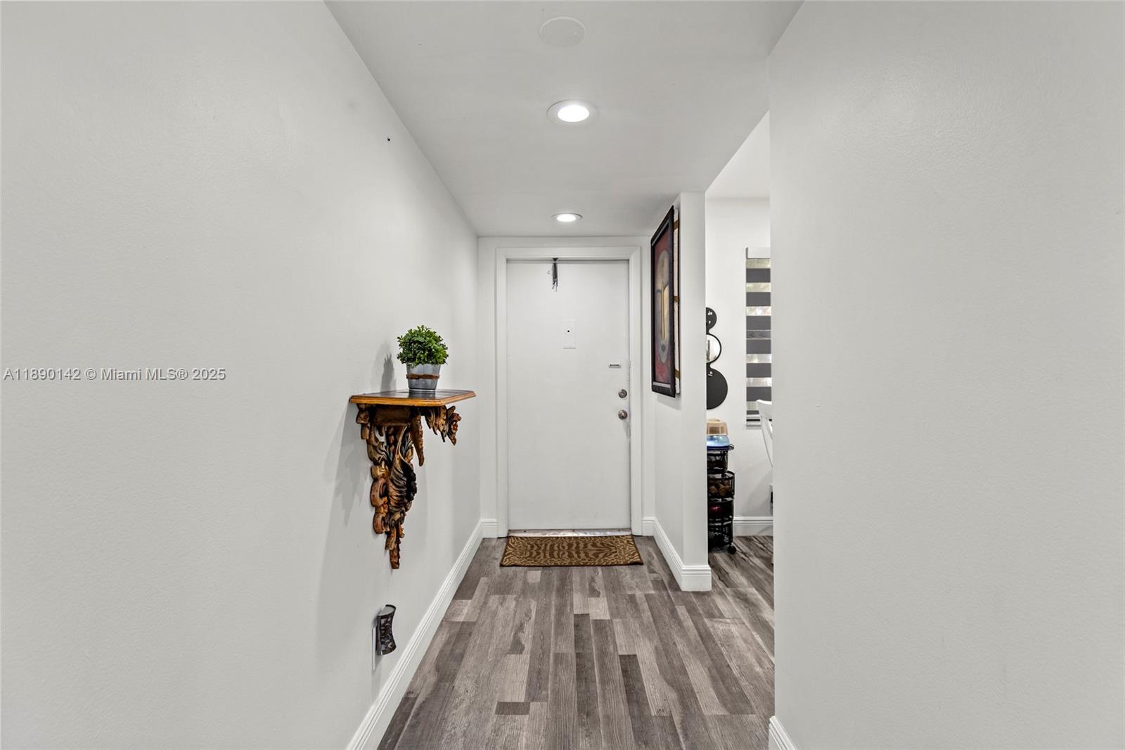 This entryway features white walls, wood-look flooring, a decorative wall shelf, and a white door — 10400 NW 30th Ct # 202, Sunrise FL 33322, SUNRISE, FL