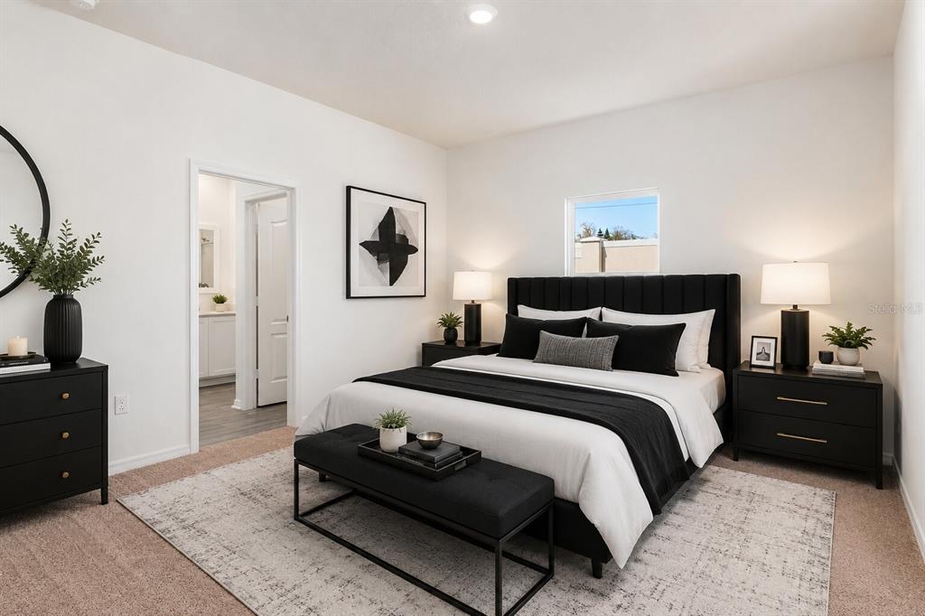 A bedroom features a black upholstered bed, matching nightstands, a bench, and a neutral rug — 1782 WHITE ELEPHANT, WINTER HAVEN, FL