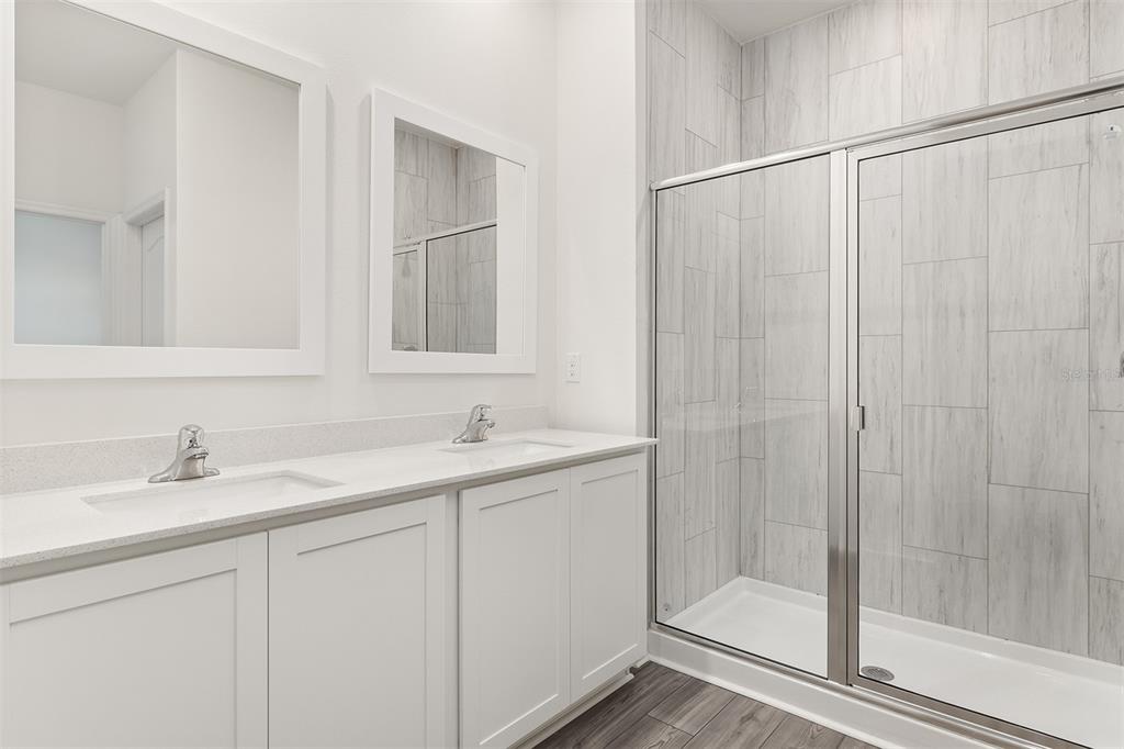 A bathroom features a double vanity with white cabinets and a tiled walk-in shower — 1782 WHITE ELEPHANT, WINTER HAVEN, FL