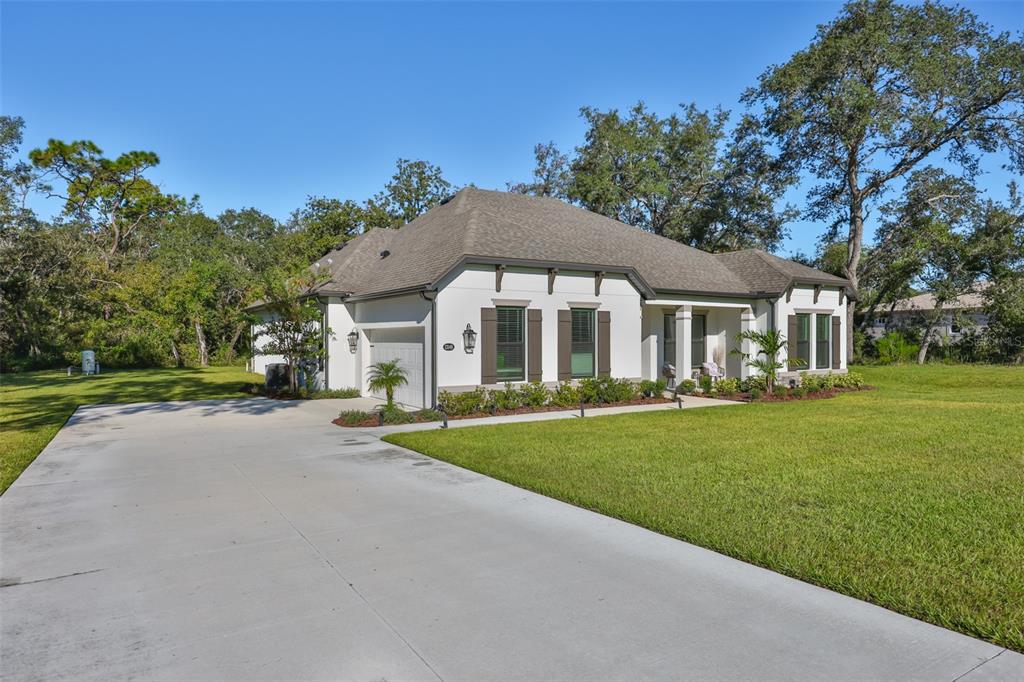 A single-story white house with a gray roof and a concrete driveway sits on grass — 13148 OLDENBURG DRIVE, HUDSON, FL